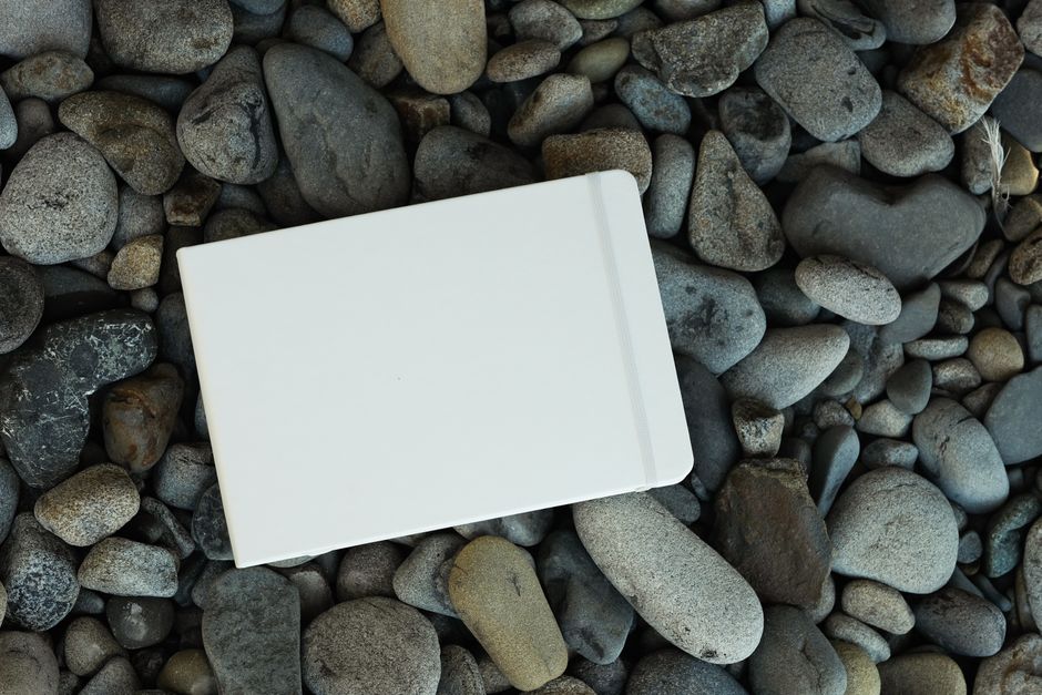White notebook on a rocky surface. Perfect for mockup designs and creative projects.
